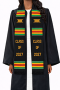 Black Class of 2027 Kente graduation stole with gold lettering, stool symbols, and green, gold, and red stripes, worn over a graduation gown